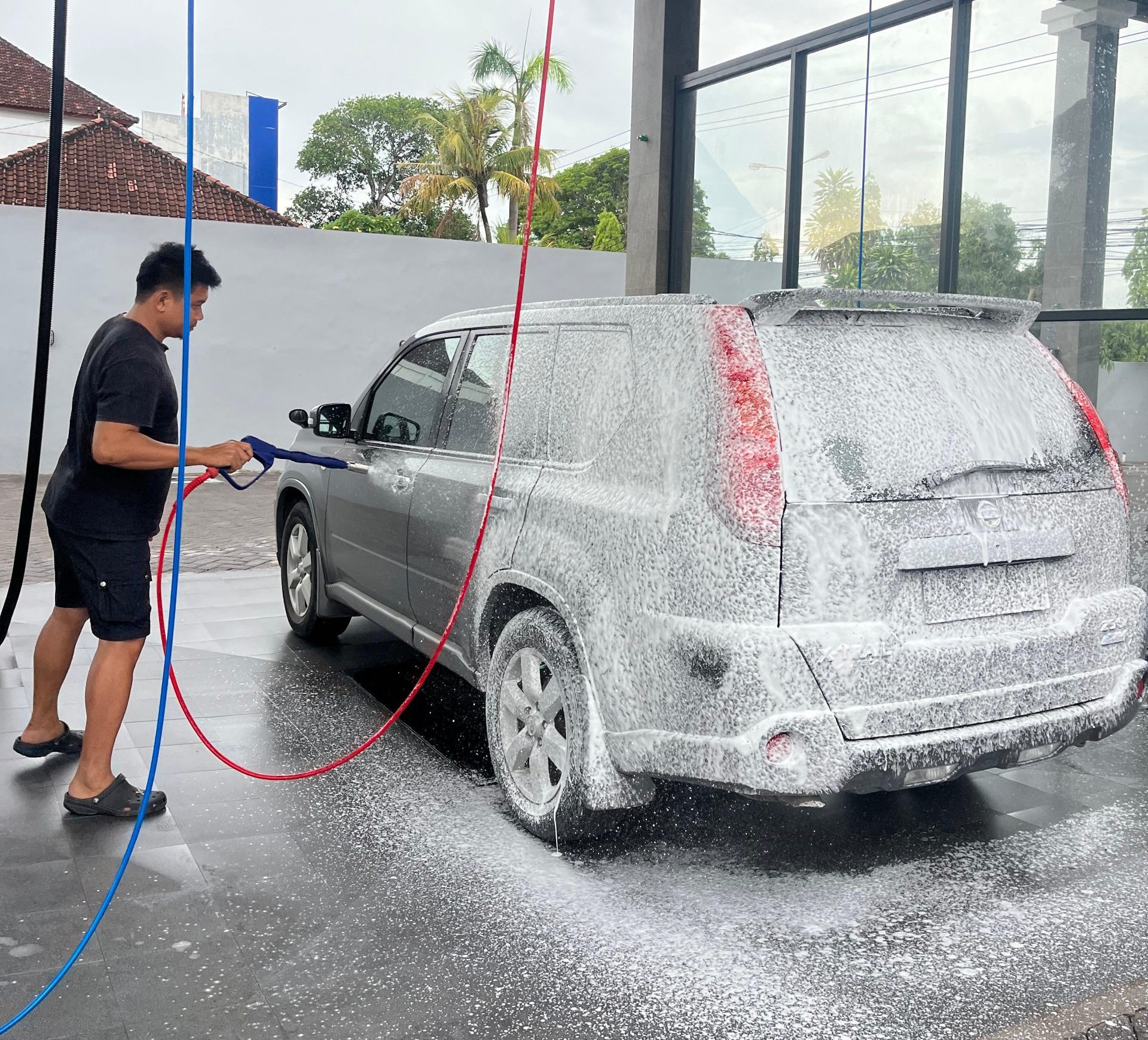 Pelanggan menyemprotkan foam sabun salju (snow wash) di fasilitas Self Car Wash Bali yang modern dan luas di Denpasar.