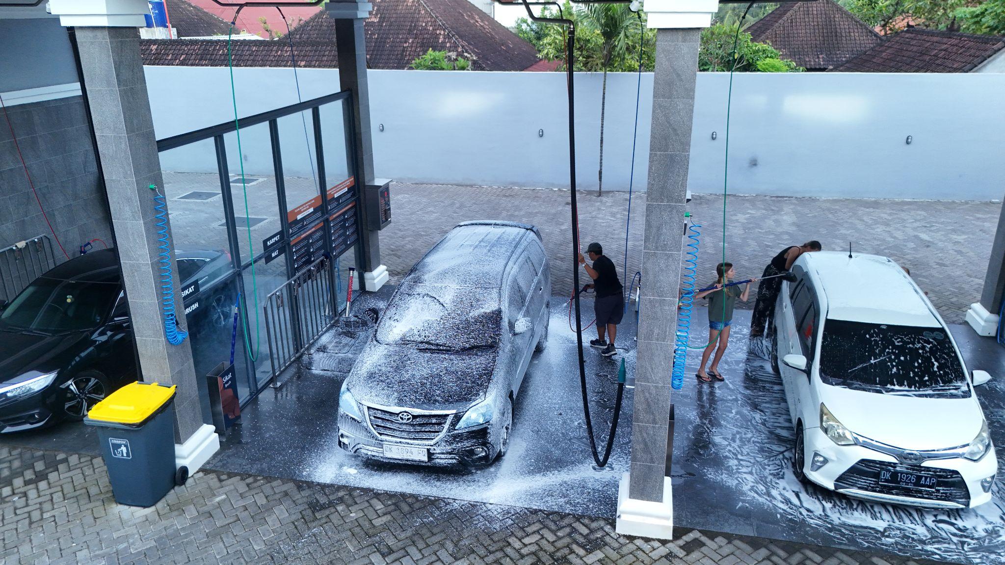 Fasilitas self car wash mobil di Bali dengan beberapa mobil sedang dicuci.