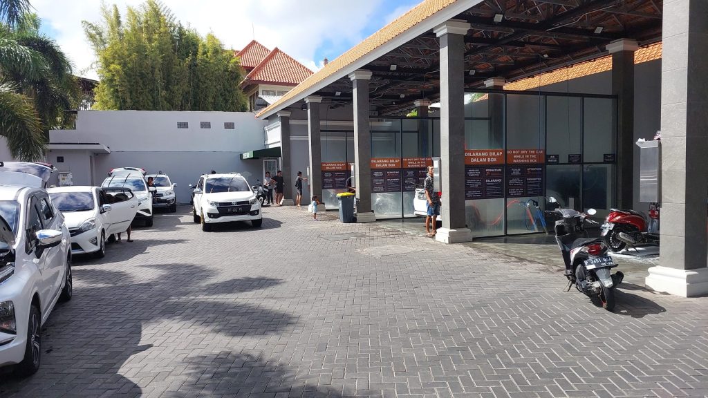 pelanggan sedang mencuci mobil sendiri menggunakan air tekanan tinggi di outlet franchise self service car wash Indonesia 24 jam